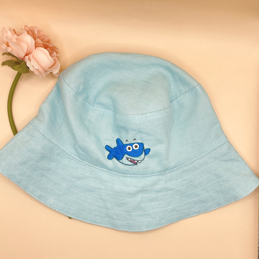 Baby Shark Embroidered Linen Baby Hat in light blue with a cute shark design by Stitchery Zone