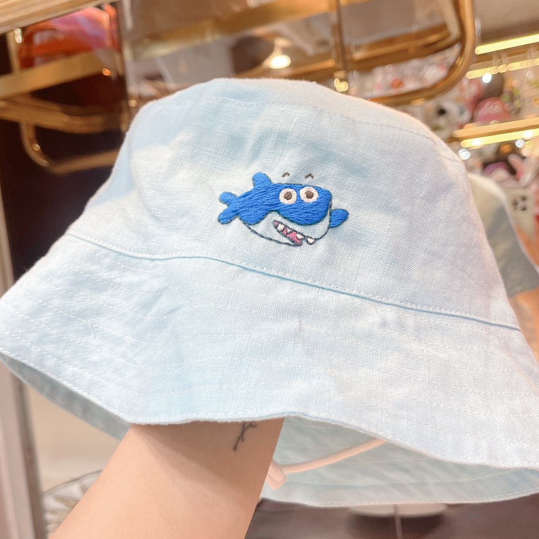 Baby Shark Embroidered Linen Baby Hat in light blue with stitched blue shark design by Stitchery Zone
