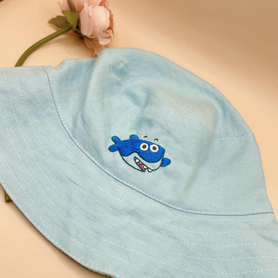 Baby Shark Embroidered Linen Baby Hat in light blue with a cute blue shark design by Stitchery Zone