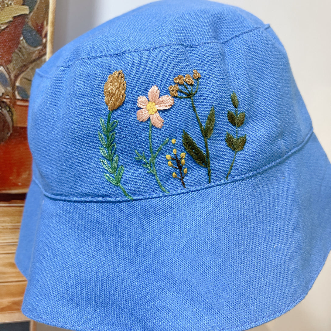 Blue embroidered Garden Linen Baby Hat by Stitchery Zone with floral design on front