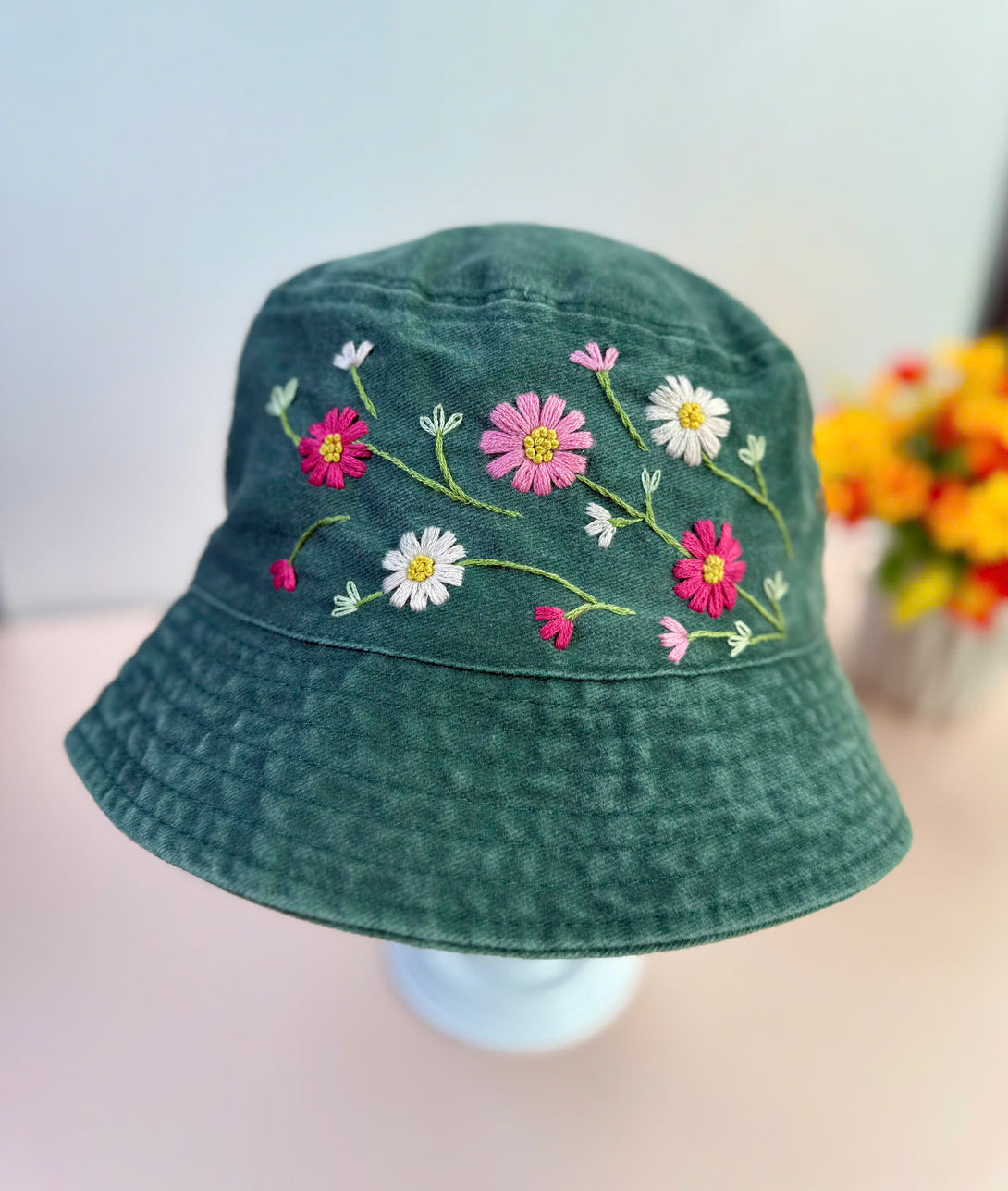 Stitchery Zone Colorful Flowers Hand Embroidered Bucket Hat with pink white floral design on green fabric