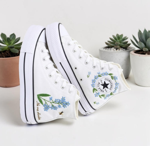 White Converse high-top shoes featuring blue flowers embroidery and a classic logo patch