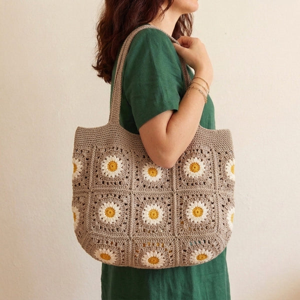 Crochet market tote bag in beige with yellow floral granny square motifs worn on the shoulder