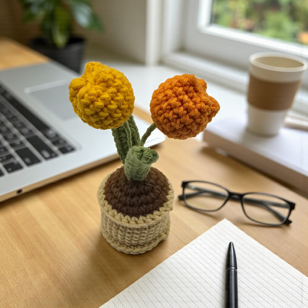 Crochet tulip in a pot with vibrant yellow flowers on a desk next to a laptop and notepad