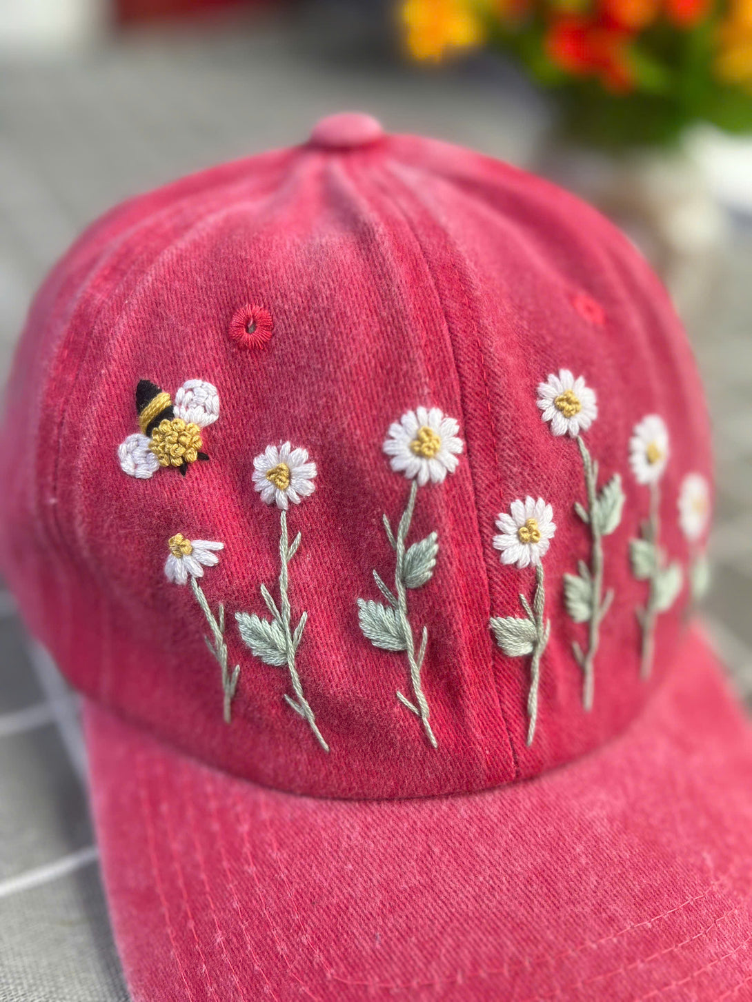 Stitchery Zone pink embroidered hat with custom floral embroidery cap design featuring daisies and a bee