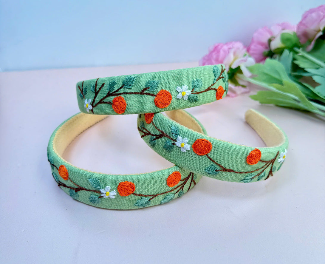 Stitchery Zone embroidered custom headbands in light green with orange and white floral embroidery design