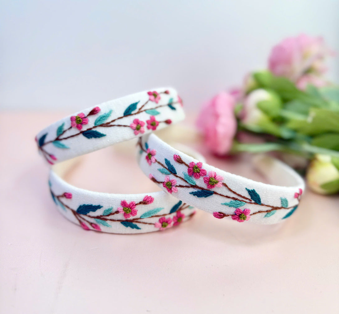 Stitchery Zone embroidered custom headbands with pink floral design on white fabric background