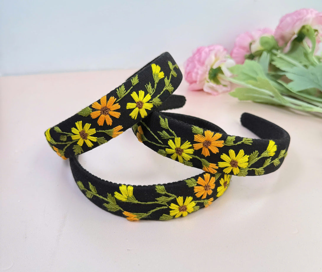Stitchery Zone embroidered custom headbands with yellow and orange floral designs on black fabric