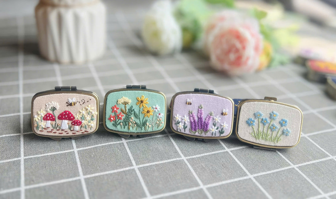 Stitchery Zone embroidered jewelry box with floral and mushroom designs on a gray grid surface
