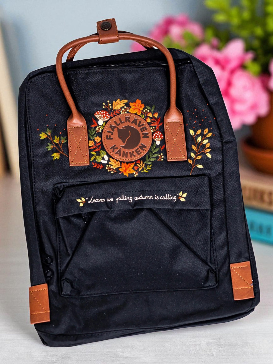 Classic Fjallraven Kanken Backpack black with leather handles and autumn floral print on front pocket