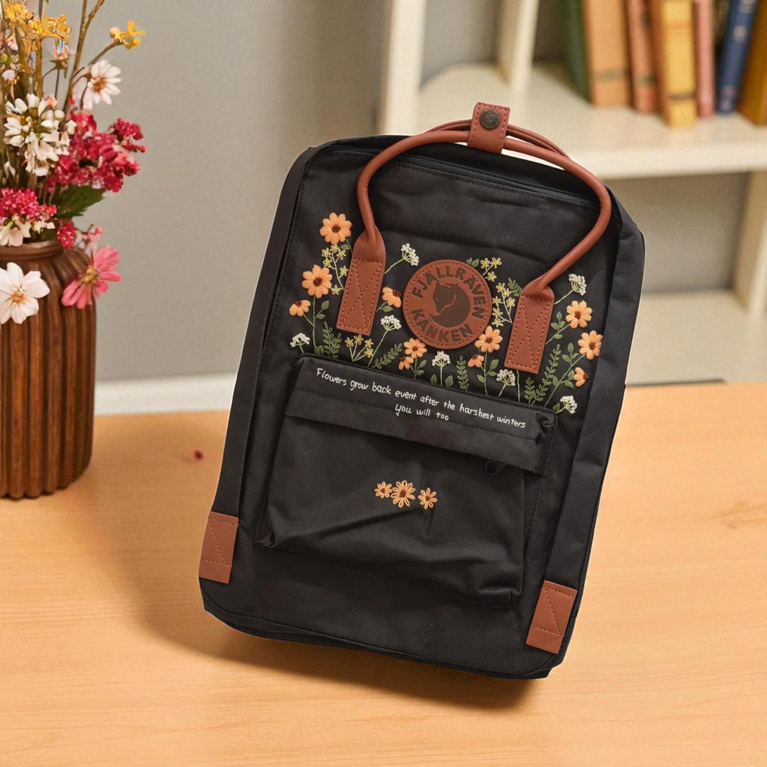 Stitchery Zone black Fjallraven Kanken Backpacks with brown leather handles and embroidered floral design
