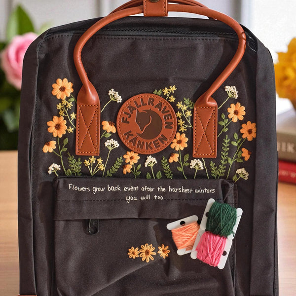 Stitchery Zone black Fjallraven Kanken Backpacks with orange floral embroidery leather handles front pocket and thread spools