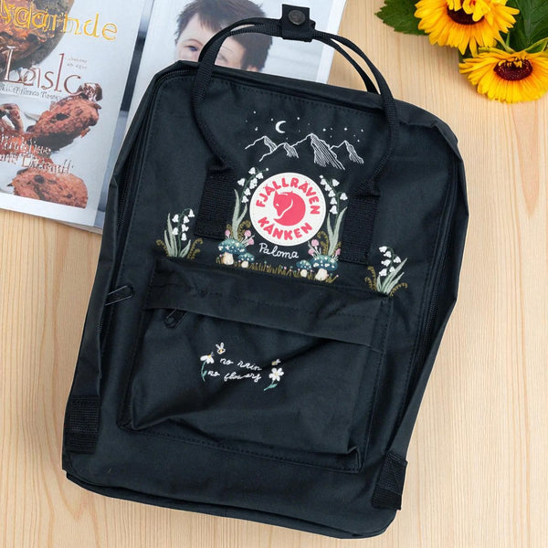 Fjallraven Kanken Classic Backpack in black with embroidered mountain and floral design, top handles and front pocket