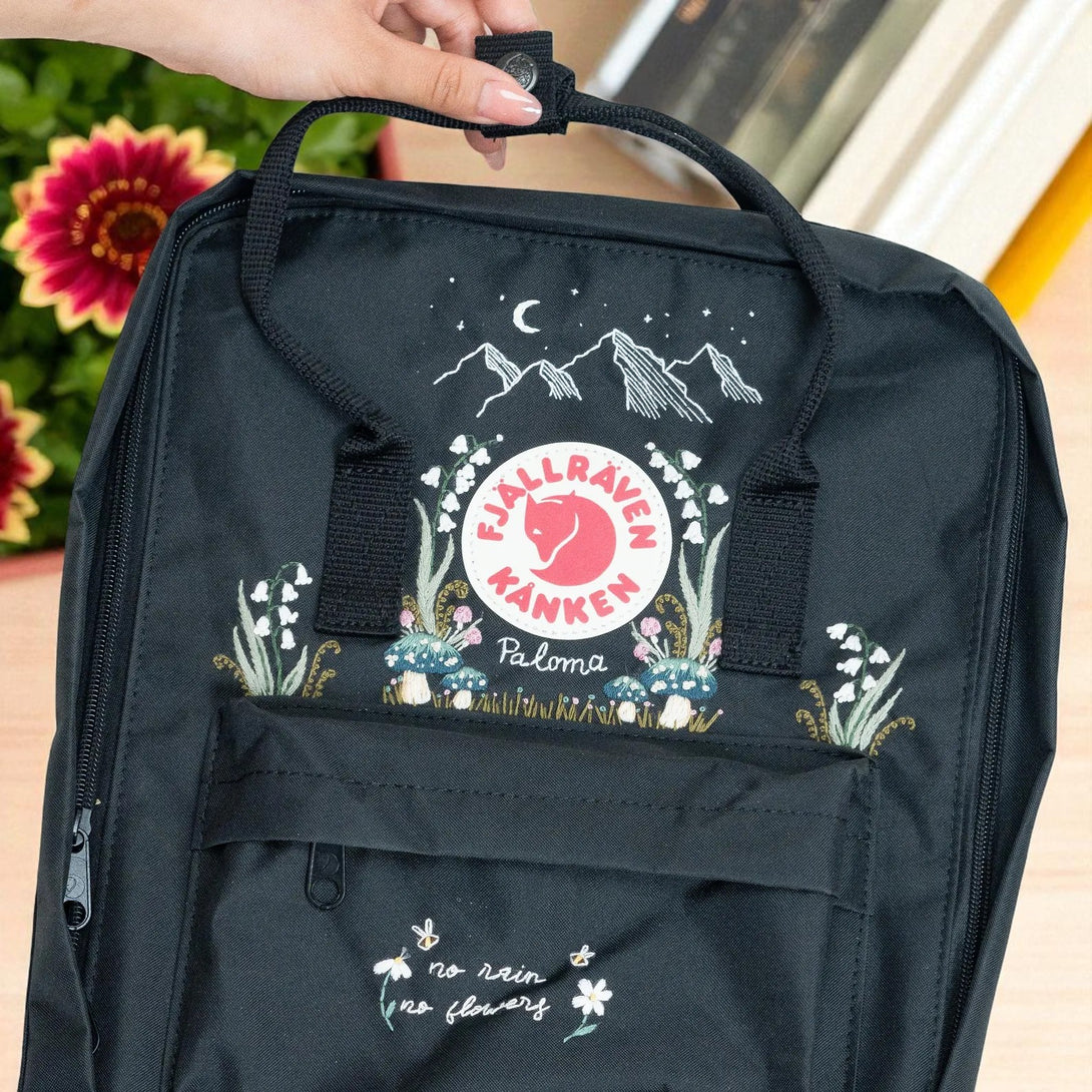Fjallraven Kanken Classic Backpack black embroidered floral mountain design front pocket with red logo and top handle