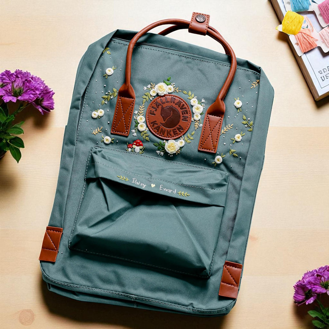 Fjallraven Mini Kanken Backpack in green with leather handles and embroidered floral design on front