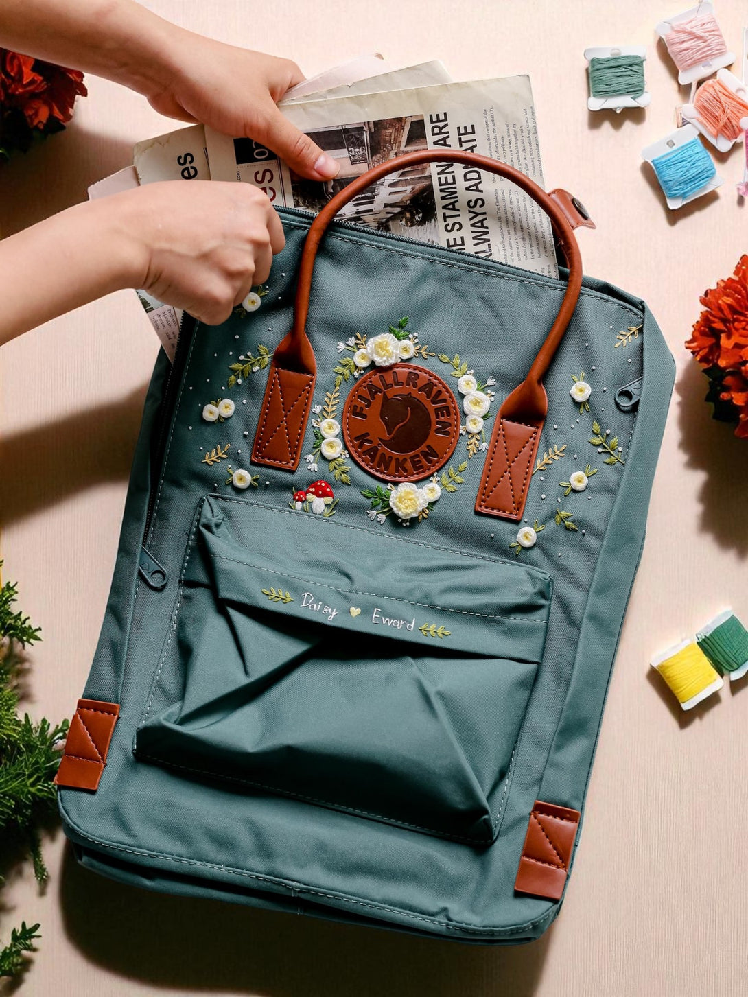 Stitchery Zone Fjallraven Mini Kanken Backpack teal with embroidered flowers brown leather handles and newspaper