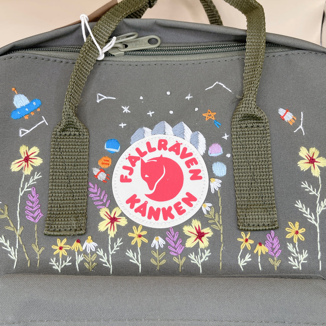 Floral kanken backpack for women in gray with colorful embroidered flowers and space-themed designs