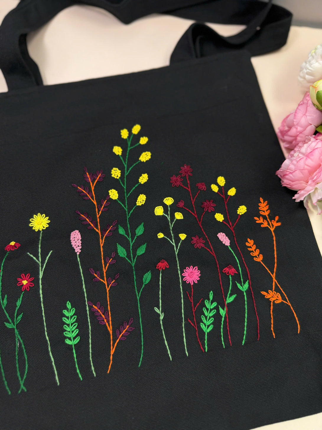 Stitchery Zone black floral embroidery tote bag with colorful stitched wildflowers and green leaves
