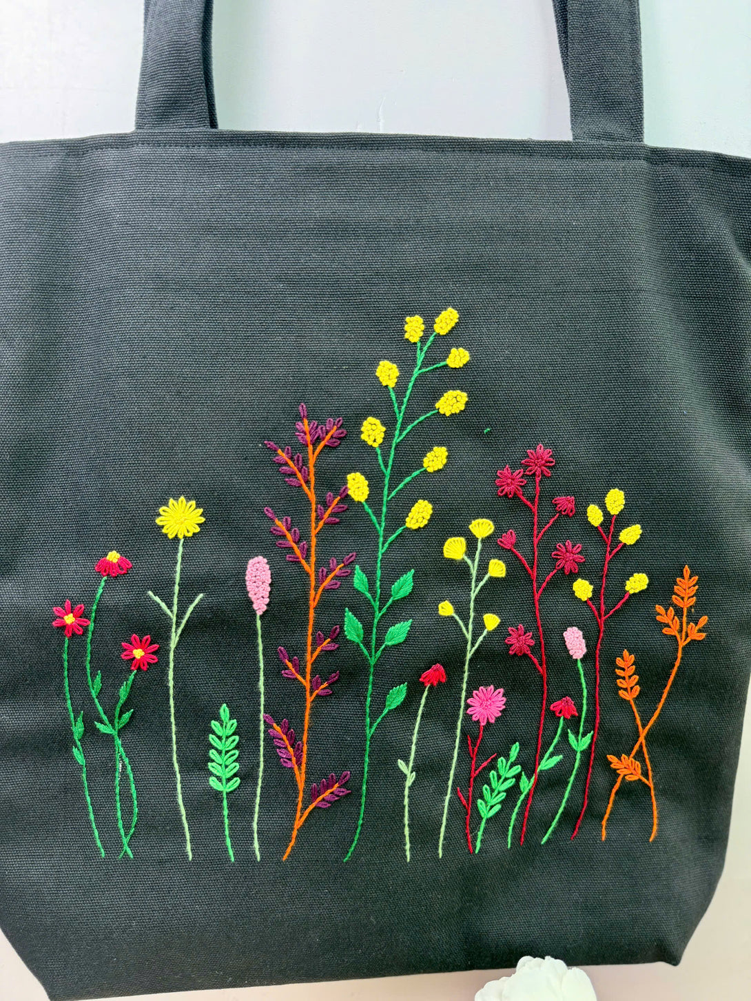 Stitchery Zone black bag with colorful floral embroidery tote design featuring various flower patterns