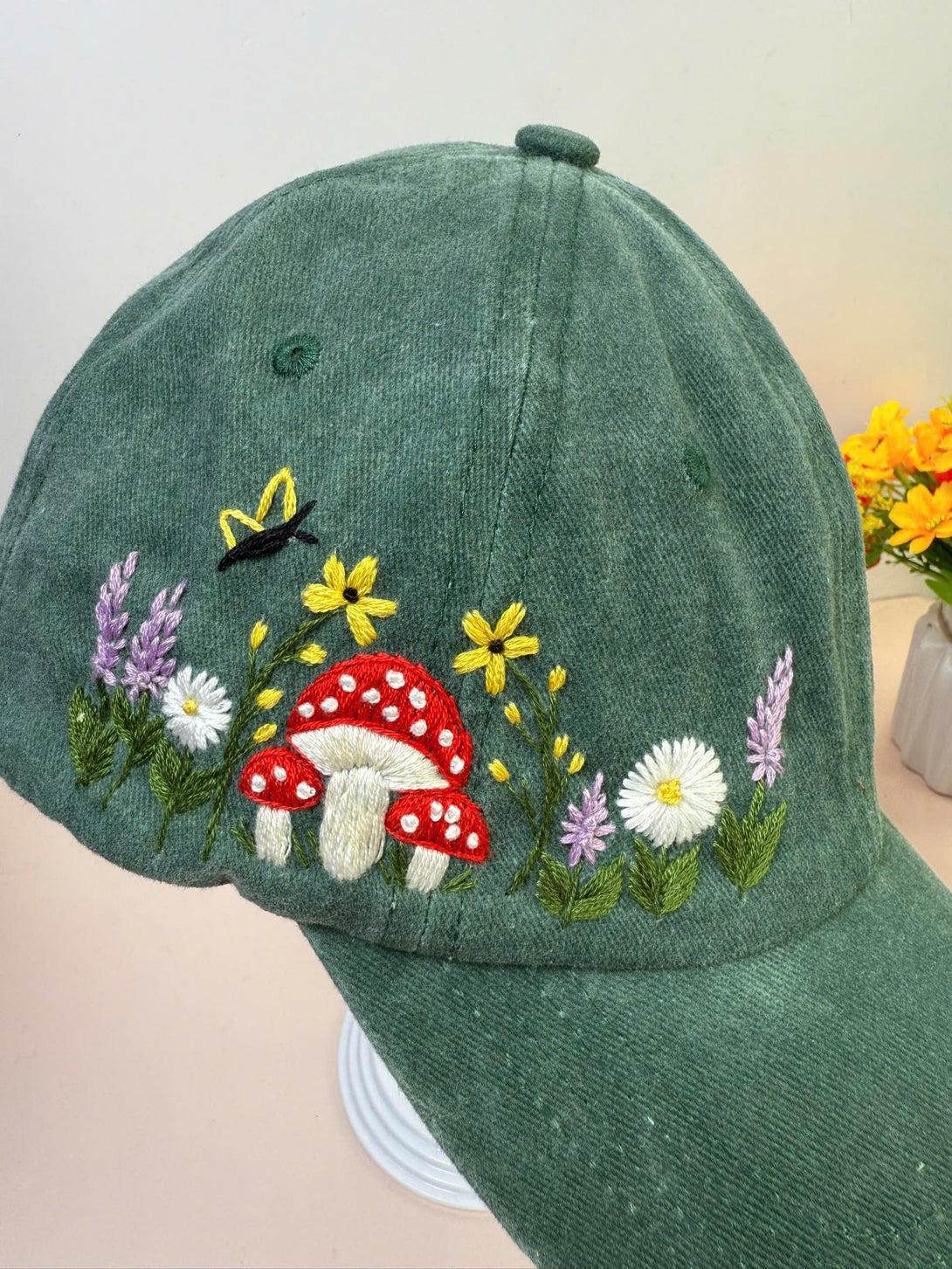 Stitchery Zone Mushroom And Flowers Hand Embroidered Hat in green with red mushrooms and colorful floral design