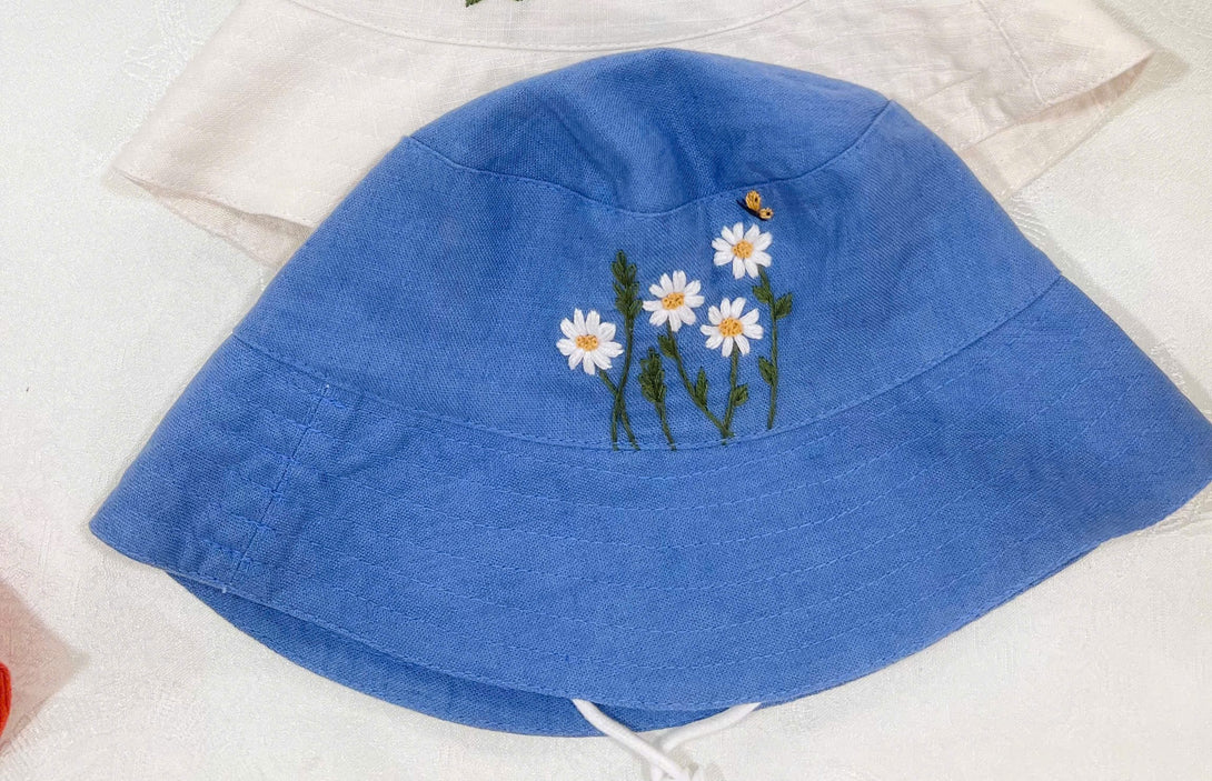 Hand Embroidered Daisy and Bee Linen Baby Hat in blue with floral embroidery from Stitchery Zone