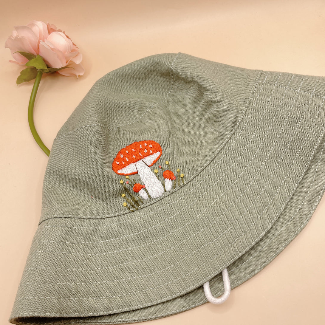Hand Embroidered Mushroom Linen Baby Hat in soft green with red mushroom embroidery by Stitchery Zone
