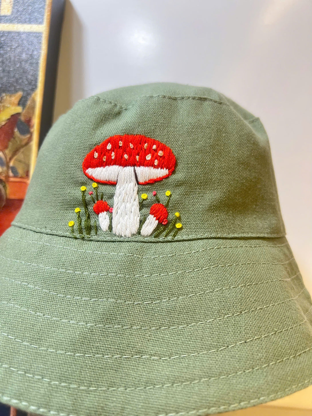 Hand Embroidered Mushroom Linen Baby Hat in green with red and white mushroom embroidery from Stitchery Zone