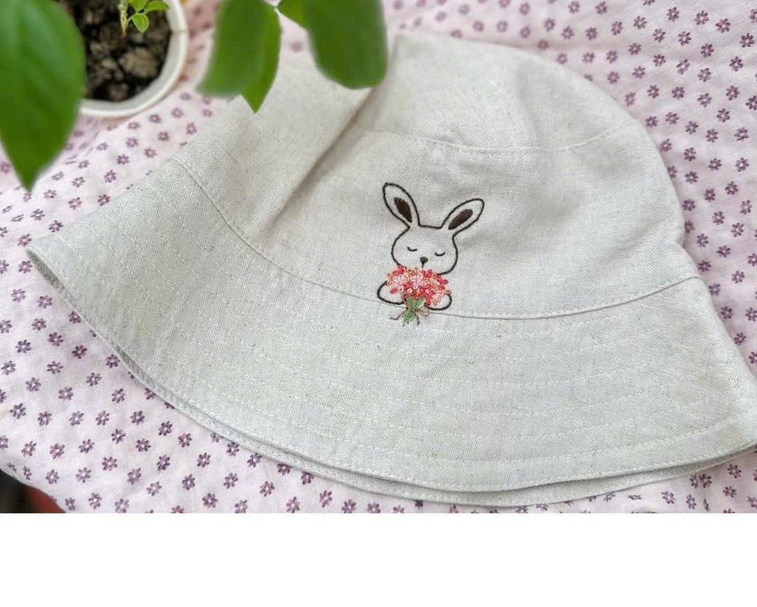 Hand Embroidered Rabbit Linen Baby Hat in light beige with cute embroidered rabbit holding flowers