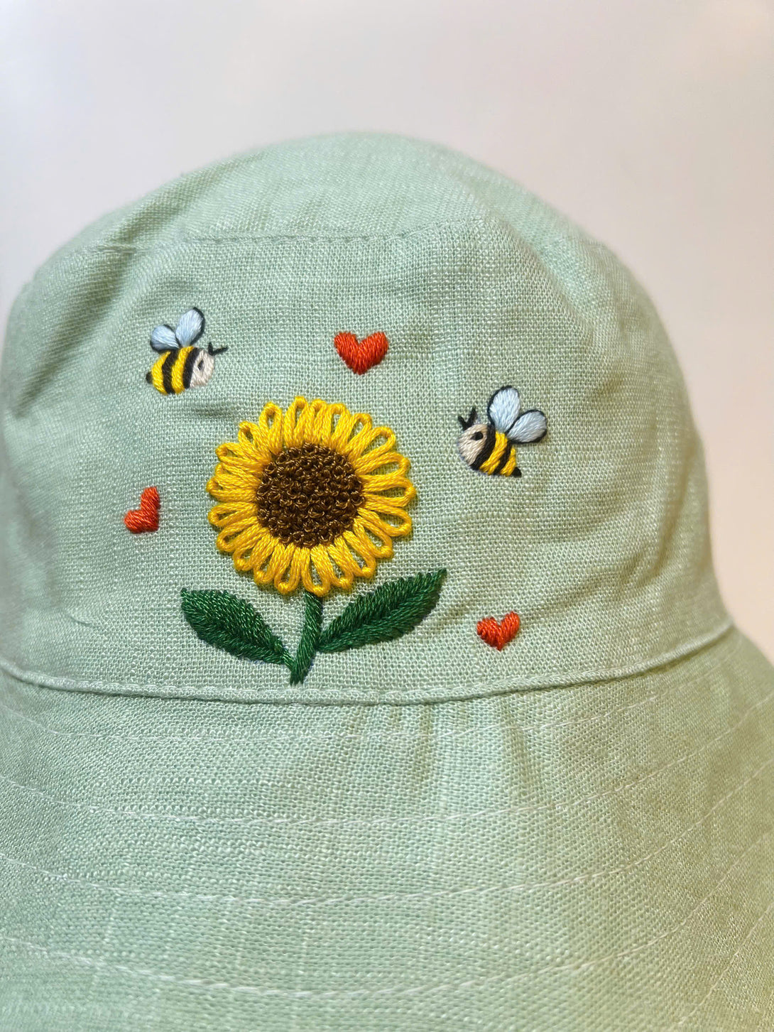 Hand Embroidered Sunflower and Bee Linen Baby Hat with green fabric and detailed stitching