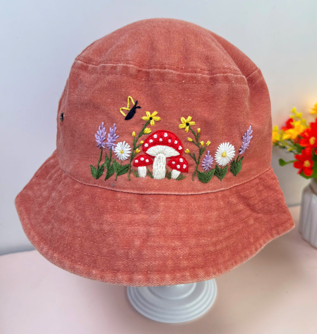 Mushroom And Flowers Hand Embroidered Bucket Hat by Stitchery Zone in faded red with colorful floral design