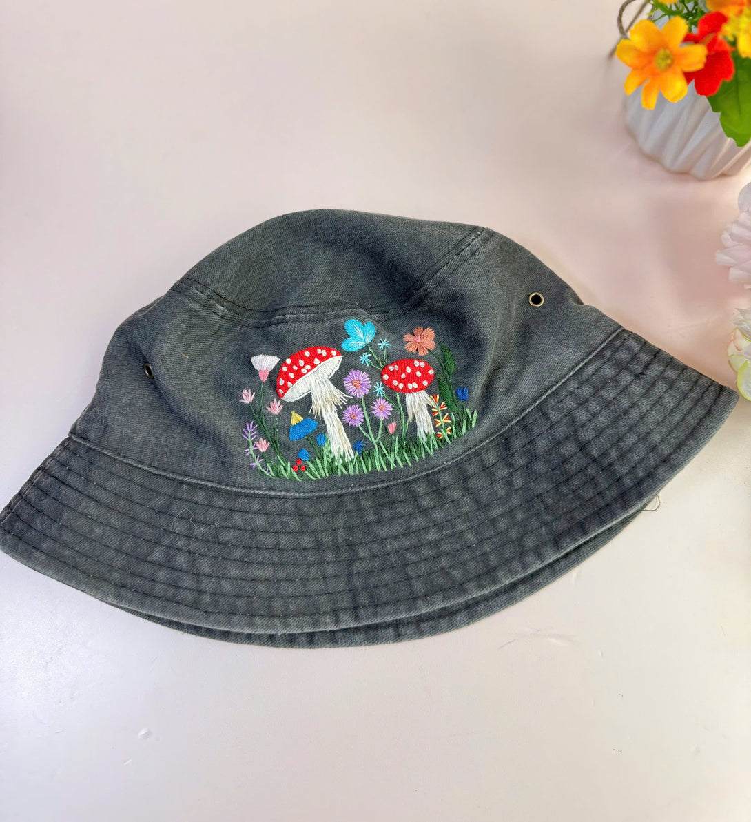 Stitchery Zone Mushroom Hand Embroidered Bucket Hat in dark fabric with colorful mushroom design and flowers