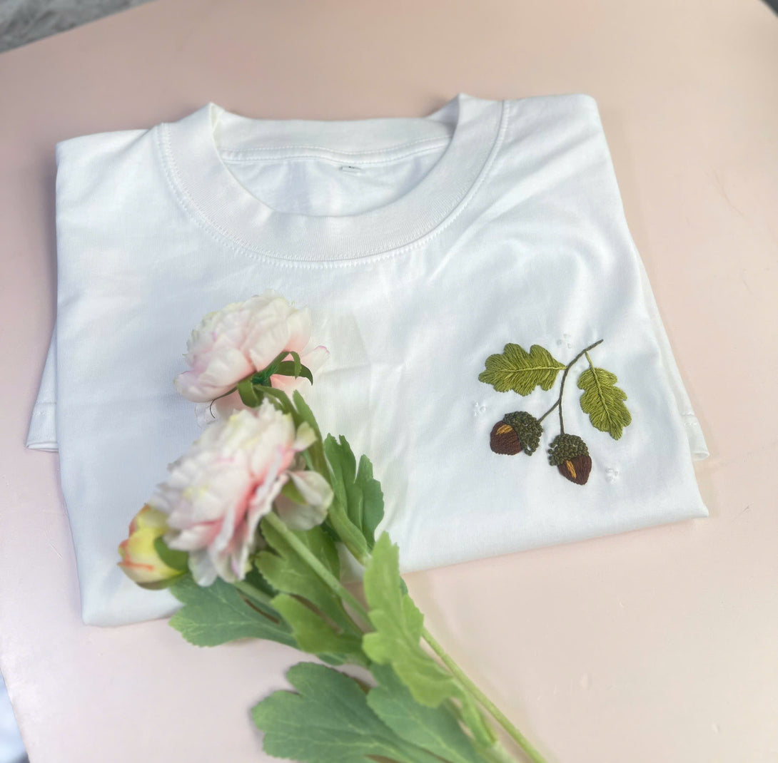 Nature inspired embroidered shirt white T-shirt with green leaf and acorn design by Stitchery Zone
