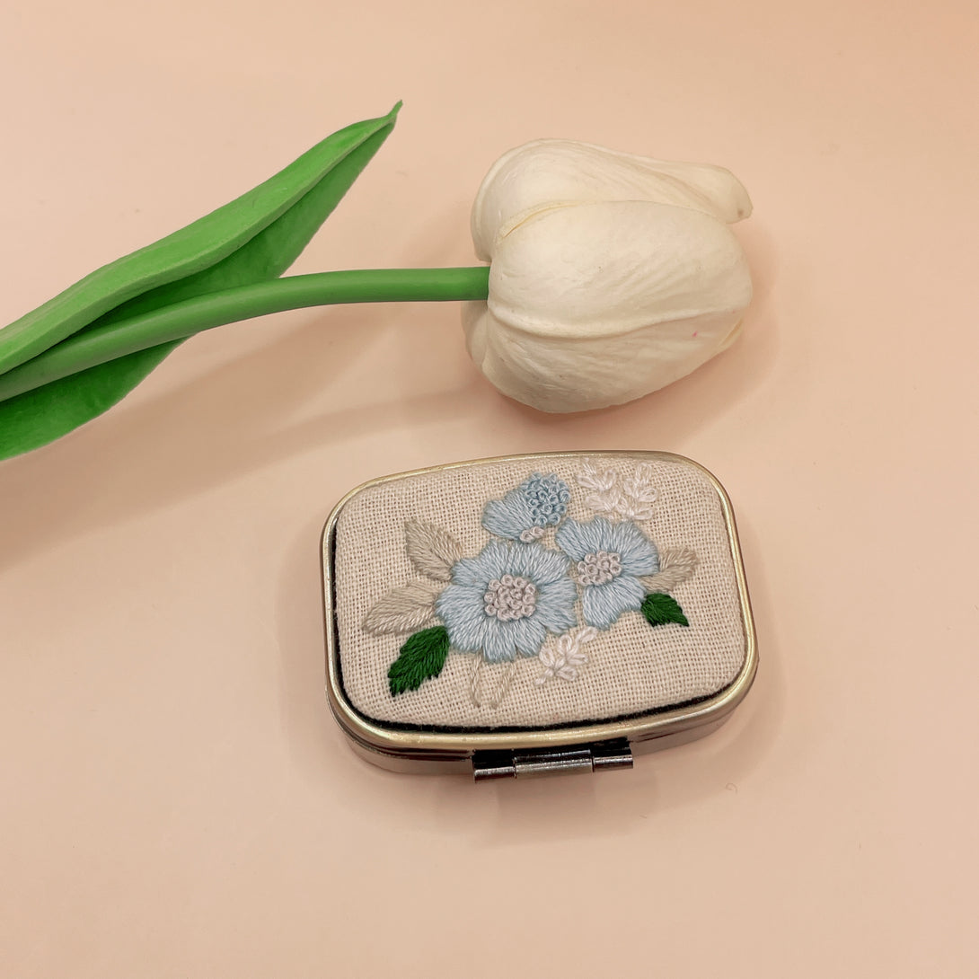Personalized Embroidered Jewelry Box with blue floral design by Stitchery Zone next to a white tulip flower