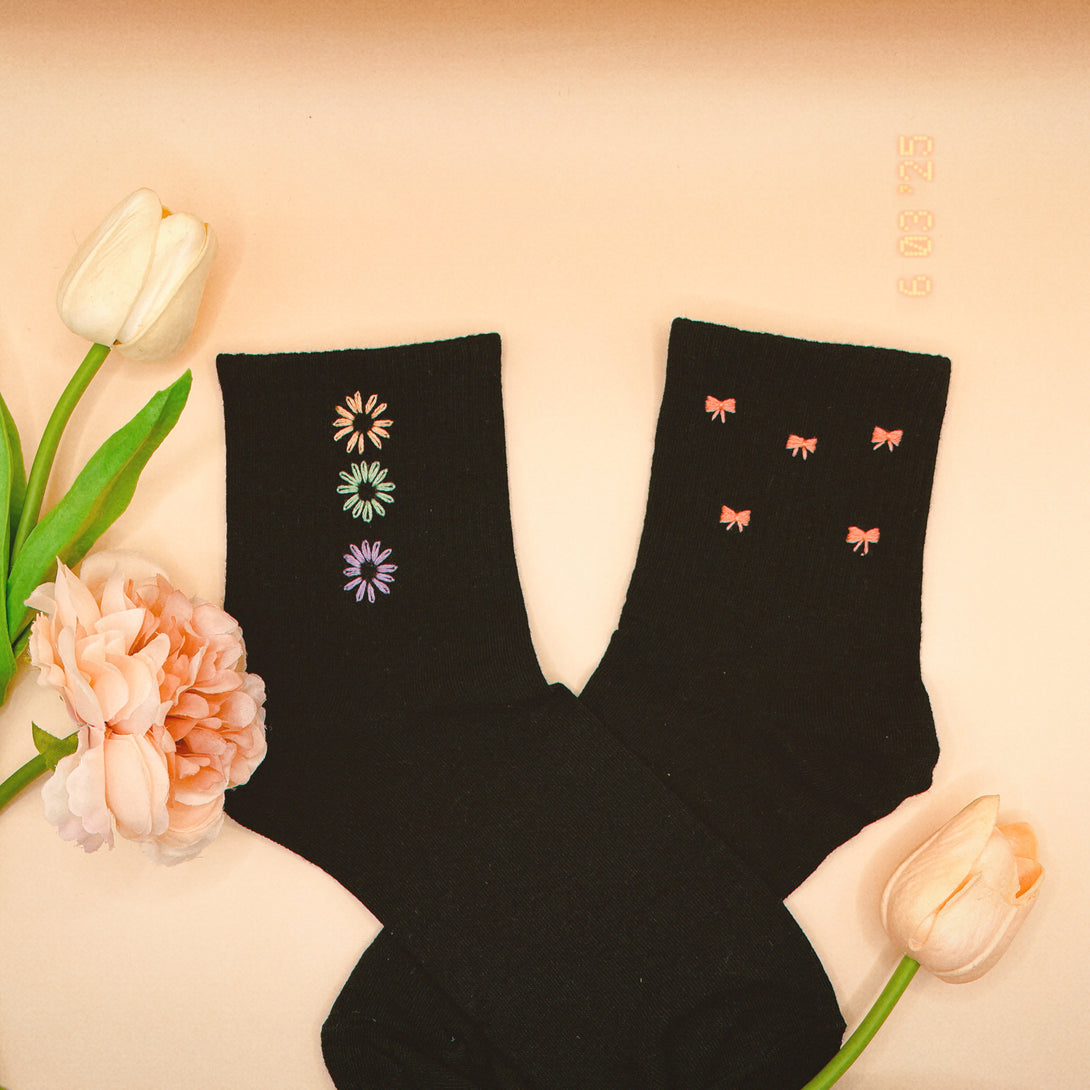 Black Style Socks Embroidered For Women with colorful flower and bow designs surrounded by soft peach flowers