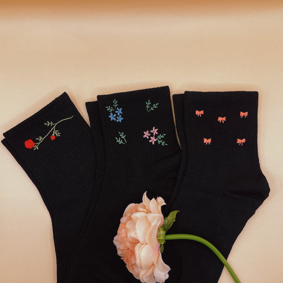 Black Style Socks Embroidered For Women with floral and bow designs displayed with a light pink flower