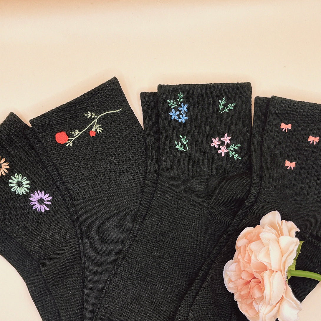 Black Style Socks Embroidered For Women with floral and bow designs displayed with a peach flower