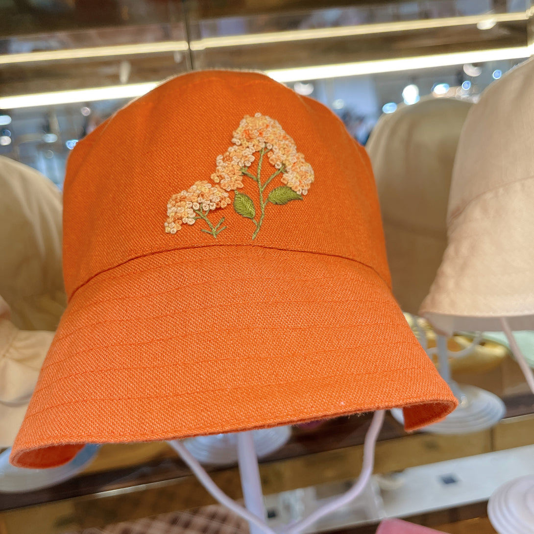 Orange Embroidered Linen Baby Hat with floral embroidery by Stitchery Zone on display