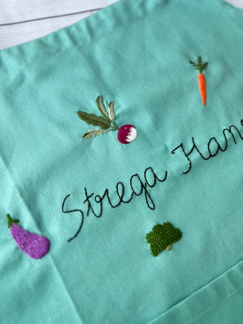 Stitchery Zone vegetable embroidery linen apron with colorful embroidered vegetables on green fabric