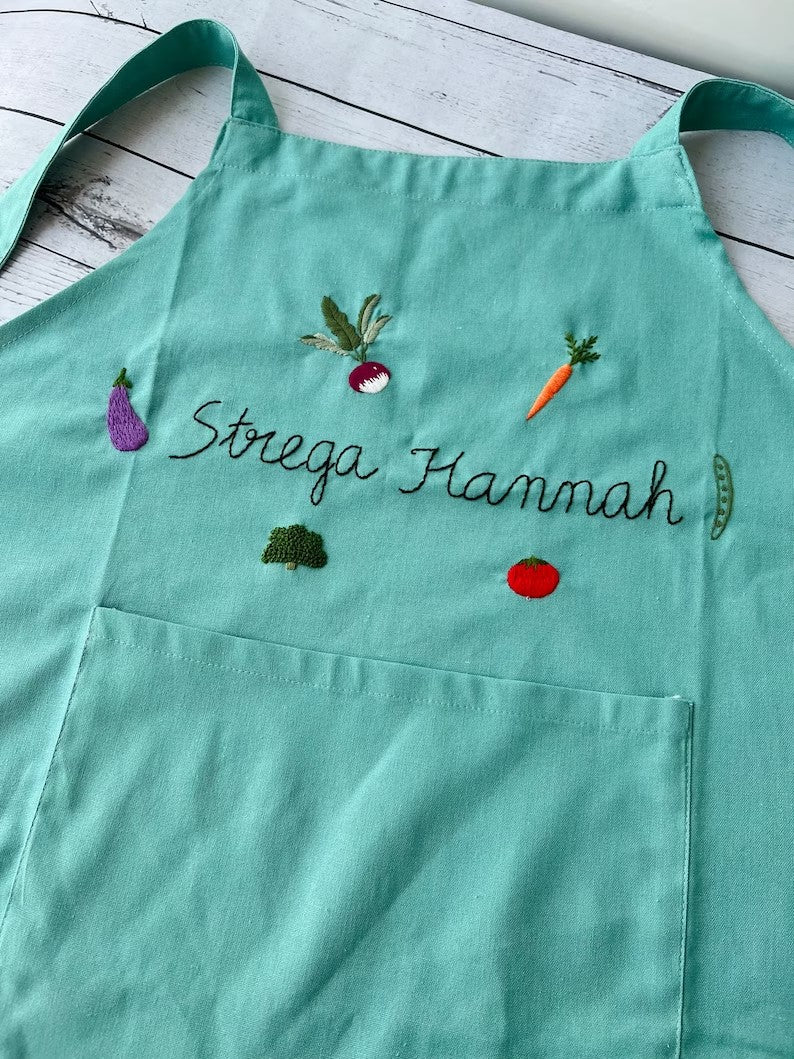 Stitchery Zone Vegetable Embroidery Linen Apron in teal with colorful vegetable designs and front pocket