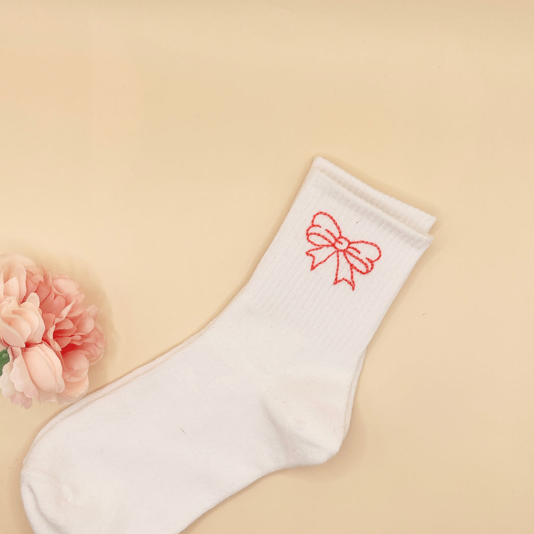 White Tennis Socks Embroidered For Women with a pink bow design displayed on beige background
